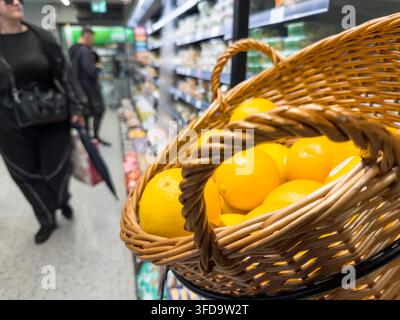 Fresh oranges in wicker display basket, supermarket fruit aisle, UK Stock Photo