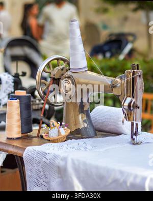 Vintage sewing machine with thread spools and lace. Traditional tailoring, needlework and craftsmanship concept. Stock Photo