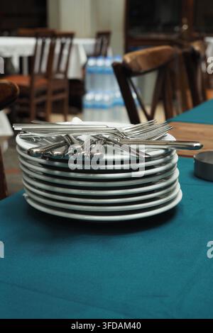 Stack of clean plates and silverware on a table Stock Photo