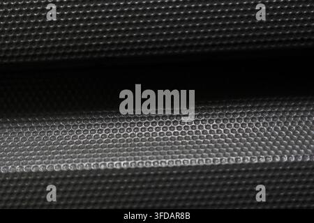 A texttextured black metal surface with raised circular pattern and horizontal highlight, creating abstract industrial background with dramatic contra Stock Photo