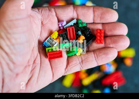 A close-up shot of colorful Lego building blocks held in a hand, representing creativity, construction, and imaginative play. Perfect for business or Stock Photo