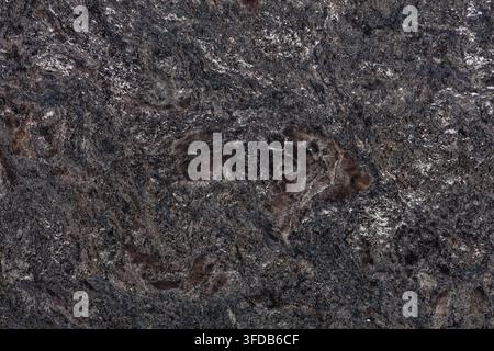 Polished dark grey granite slab surface showing brown and black mineral grains with silver speckles, a natural stone texture background for interior Stock Photo