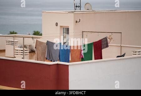 Various pieces of laundry in different colors hanging on a rooftop terrace with ocean view Stock Photo