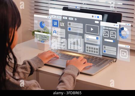 A female student using on a laptop with translucent UI UX design and application layout interfaces Stock Photo