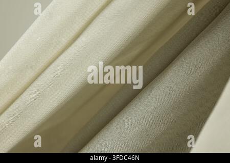 Natural linen-like fabric showing soft folds and neutral texture as background Stock Photo