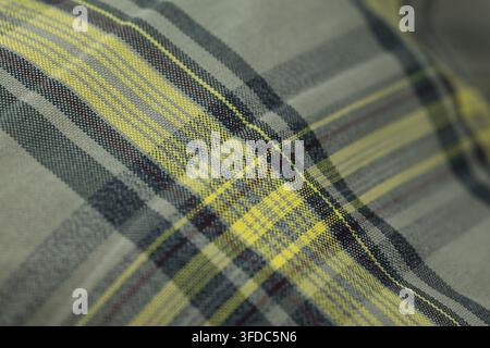 Plaid pattern in yellow, grey, black, and red threads creating a woven textile background Stock Photo