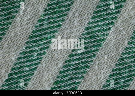 Woven green and white threads forming diagonal stripes on a textured fabric surface Stock Photo