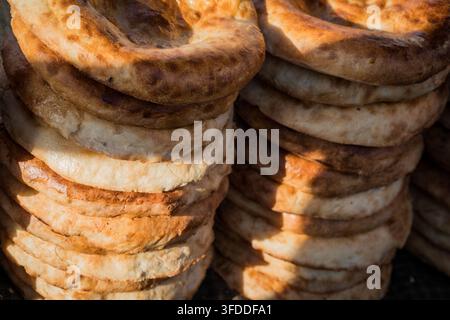Two tall stacks of circular Kyrgyz Naan bread are visible, with the crusts baked golden brown and darker toasted spots, indicating a tandoor-style bak Stock Photo