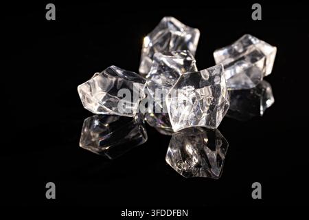pile of transparent acrylic ice cubes on glossy black surface with reflections for cold drink beauty or product background Stock Photo
