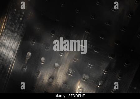 perforated black metal surface with motion blur and reflected light for abstract industrial background or technology design Stock Photo