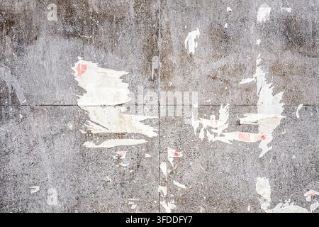 Grungy grey tiled wall texture featuring paper scraps and urban wear. Ideal background for industrial, street art, and grunge design concepts. Horizon Stock Photo