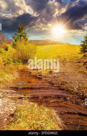 sunset over rural scenery in carpathian mountains. simple view of a countryside mountain landscape during springtime. brook near the grassy hills. wea Stock Photo