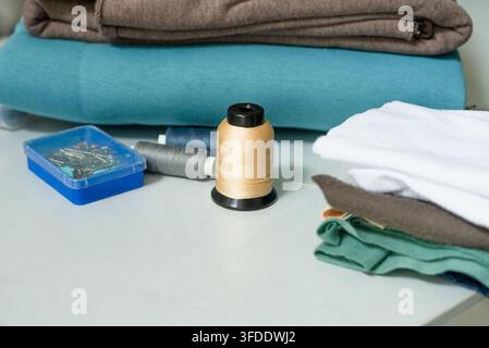 Sewing supplies arranged on white craft table for creative hobby. Thread spools and sewing kit displayed for textile crafting. Inspiring collection of accessories ready for productive needlework Stock Photo