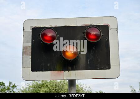 Closeup industrial signal panel with two red lights, amber light, blue sky background Stock Photo