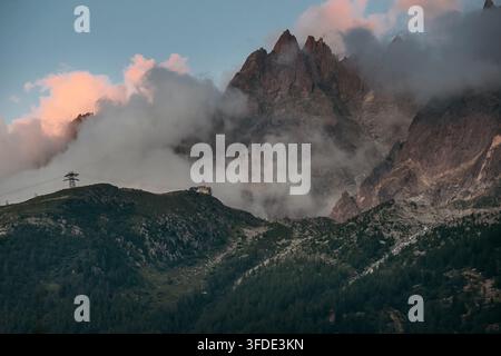 Dramatic sunset colors on clouds over rocky peak of Aiguille du Plan in Chamonix French Alps with misty fog rolling across mountain ridge during beaut Stock Photo