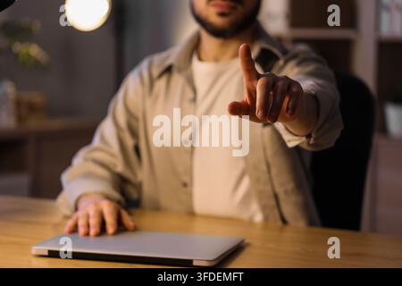 Digital transformation and innovation, man interacting with virtual interface or touchscreen technology in modern office workspace at night Stock Photo