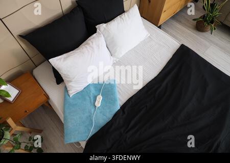 Blue electric heating pad on bed in room, top view Stock Photo