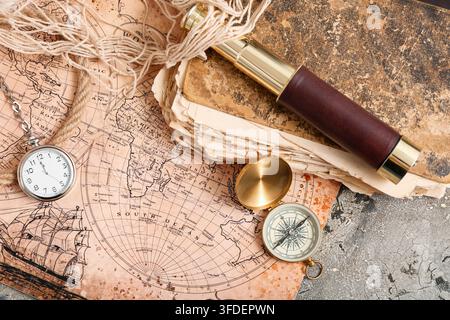 Golden compass, world map, spyglass, pocket watch and old book on grey grunge background Stock Photo