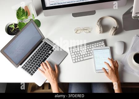 Female programmers hands working with laptop and tablet computer on table, top view Stock Photo