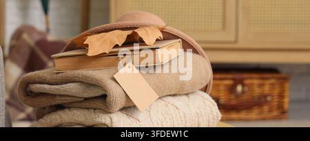 Autumn comfort and seasonal transition, stack of warm knitted sweaters with a book and dry leaves for cozy home lifestyle and fall fashion retail Stock Photo