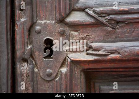 Detail of ancient rusty iron keyhole on old cracked wooden door Stock Photo