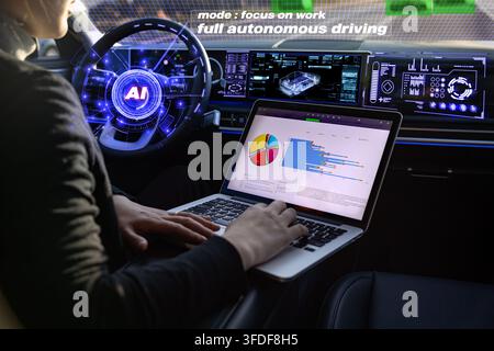 Korean woman working on a laptop inside an AI powered autonomous car with a futuristic interface Stock Photo