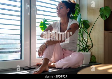 Female diabetes patient with CGM sensor in bright apartment Stock Photo