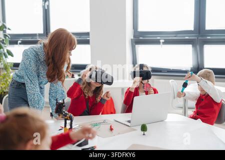 Primary school students exploring virtual reality during technology class. Stock Photo
