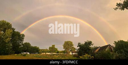 Beautiful double rainbow over a rural village landscape after summer rain Stock Photo
