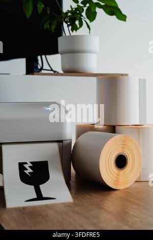 Packaging printer with rolls of labels and fragile shipping symbol for small business fulfillment. Packaging automation streamlines order processing Stock Photo