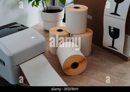 Label printer, paper rolls and fragile shipping labels for small business order fulfillment. Packaging automation streamlines ecommerce operations and Stock Photo