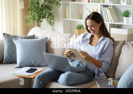 Happy telecommuter reading paper documents working sitting on a couch at home Stock Photo