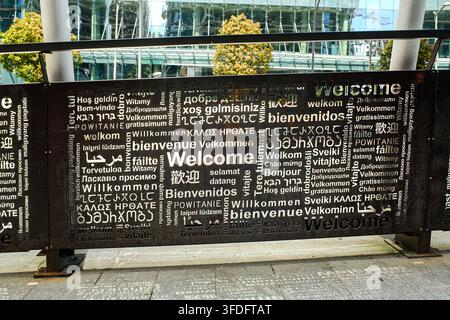 Batumi, Georgia - May 20, 2026: Part of pedestrian bridge metal fence with carved word welcome in different world languages against modern architectur Stock Photo