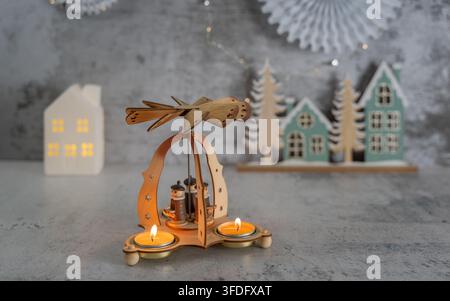 Cozy Christmas still life featuring a decorative lantern with glowing candles surrounded by miniature winter houses and seasonal greenery on a rustic Stock Photo