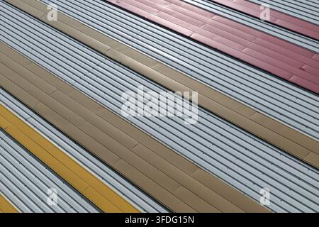 Corrugated metal facade showing horizontal lines and diagonal colored panels, forming an abstract industrial background with geometric texture and rep Stock Photo
