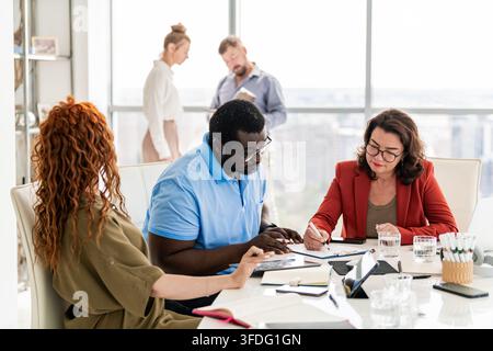 Diverse team collaborates in modern office meeting Stock Photo