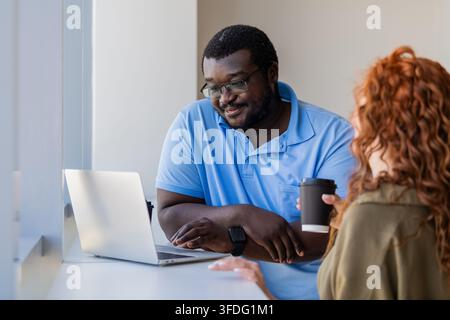 Smiling man shows coworker something on laptop Stock Photo