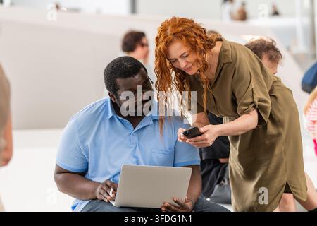 Diverse colleagues collaborating over laptop and phone Stock Photo
