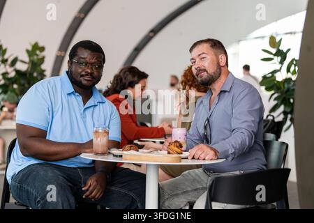 Two diverse male friends enjoying coffee at a cafe Stock Photo