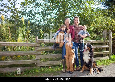Smiling family of five posing with their dog outdoors Stock Photo