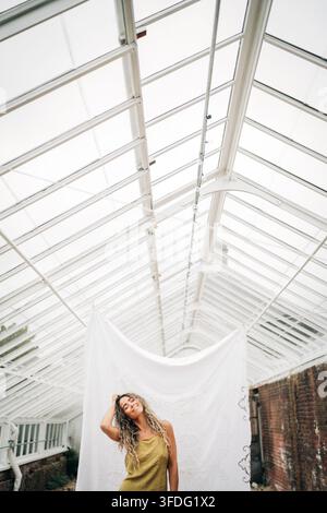 Serene woman with curly hair in greenhouse Stock Photo