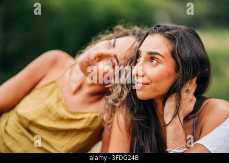 Two women with bright makeup relaxing together outdoors Stock Photo
