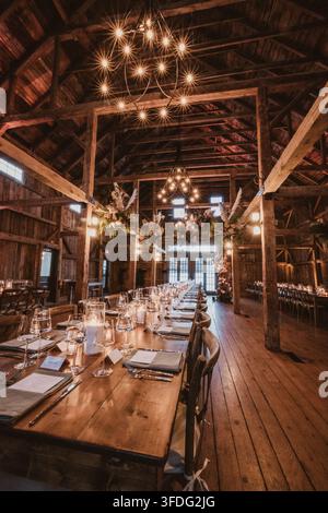 Long wooden table set for rustic barn wedding reception Stock Photo