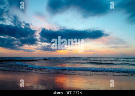 Colorful sunset sky reflecting on wet beach sand Stock Photo