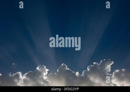 Sunbeams emerging from behind dark clouds, creating a hopeful and spiritual sky scene Stock Photo
