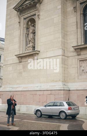 Senior man using phone in historic Budapest square Stock Photo