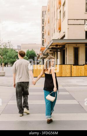 Woman looking back leading boyfriend down city street Stock Photo