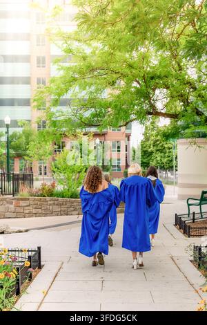 Young female graduates walking together outdoors Stock Photo