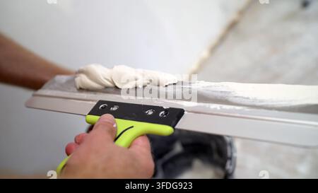 Builder smears a putty knife with a spatula. Worker puts mortar on a construction spatula. Stock Photo
