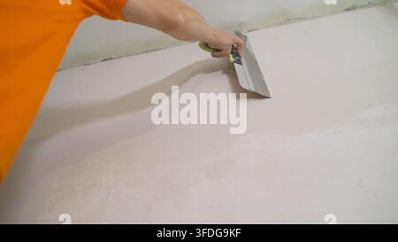 The worker processes the wall with putty. Hand with putty knife repair wall, Hand with a spatula, spatula with spackle paste structure, process of Stock Photo